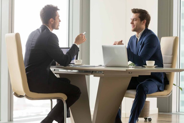 Due uomini al tavolo che conversano delle differenze commercialista e consulente lavoro
